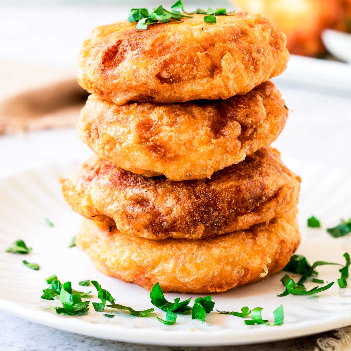 Close up of a stack of potato fritters garnished with parsley.
