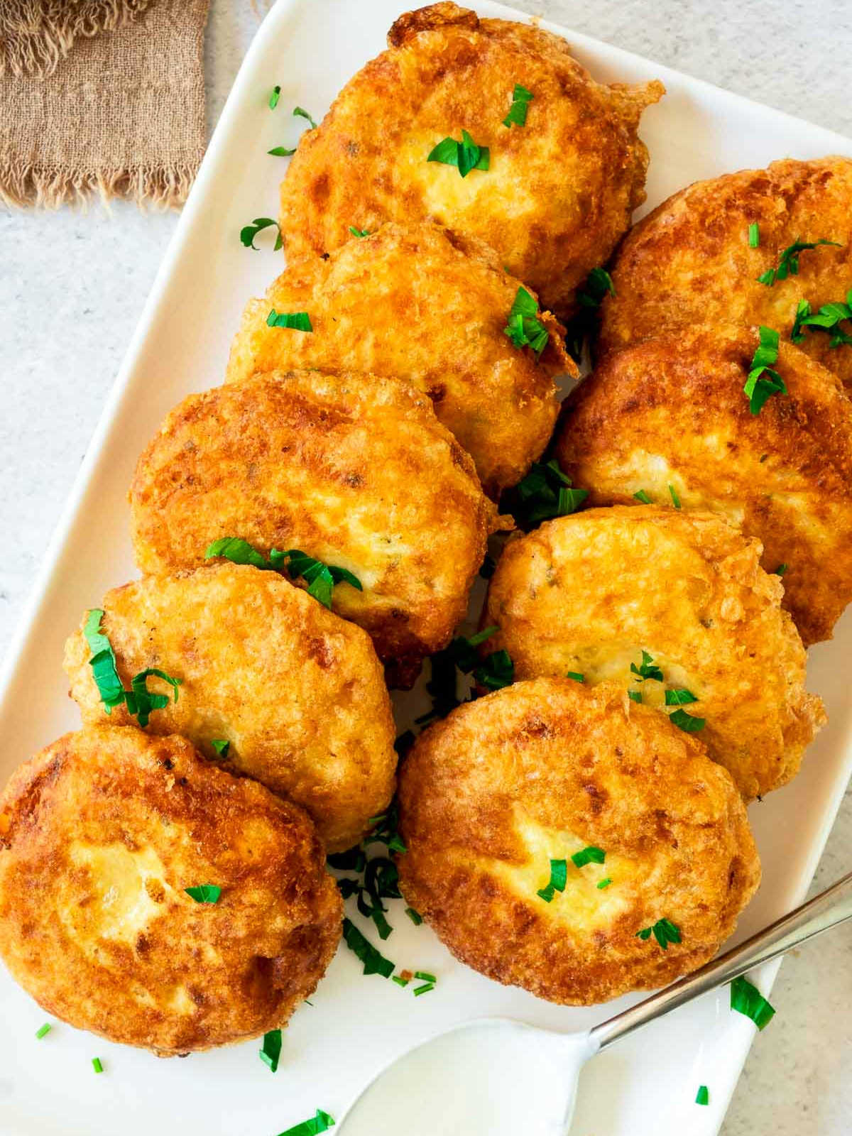 Fried potato fritters placed on a white rectangular plate for serving.
