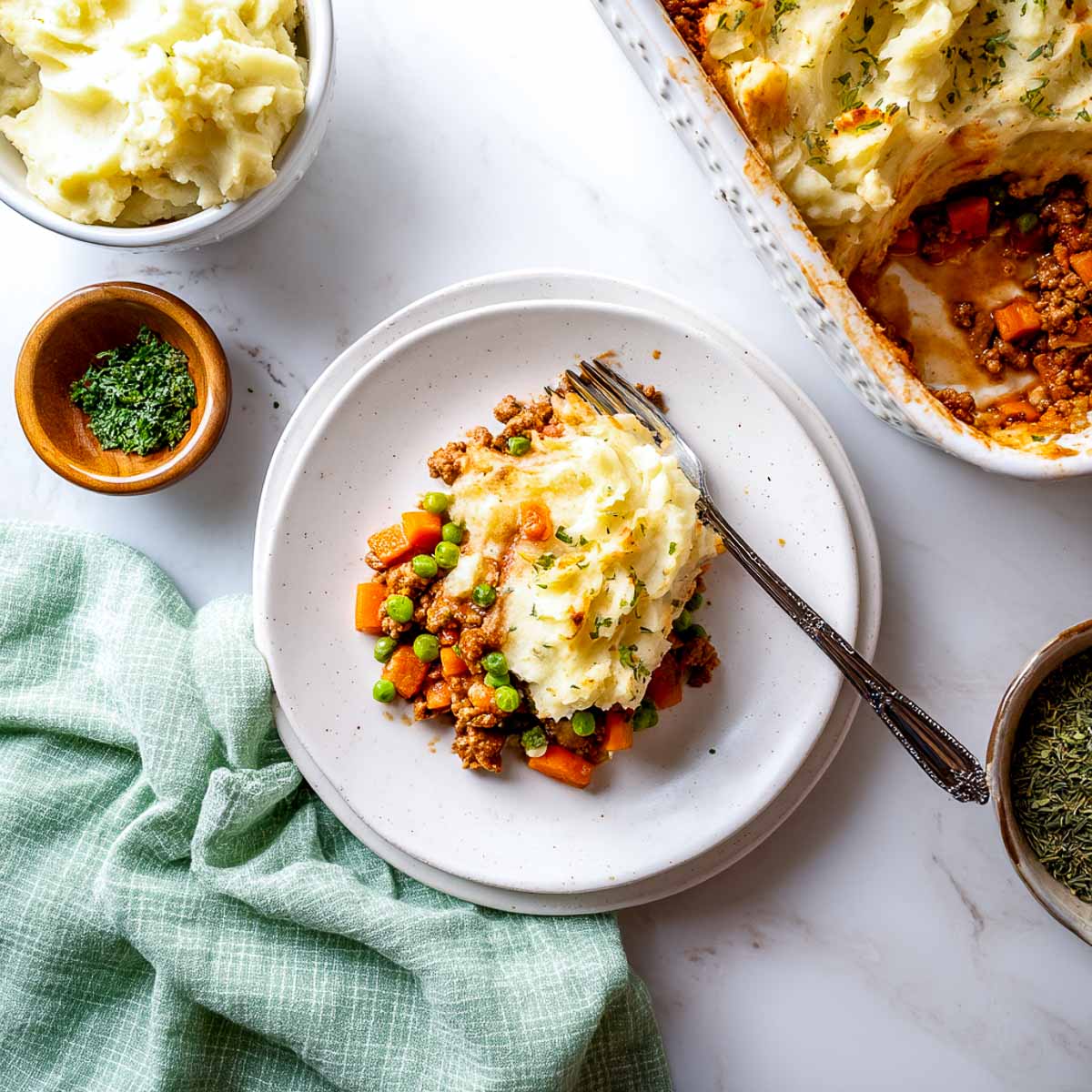 Shepherd’s pie with mashed potatoes, peas, carrots, and turkey served on a plate.