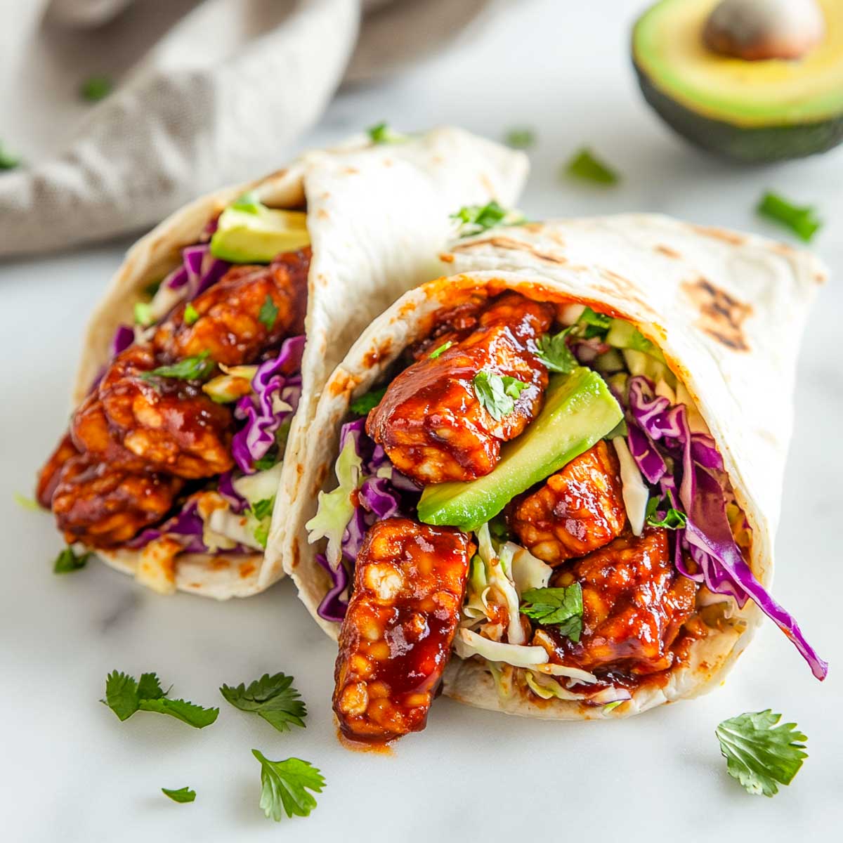 BBQ tempeh wraps with an avocado in the background.