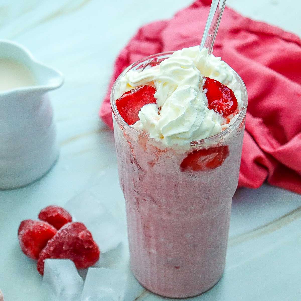Starbucks Strawberry Cheesecake Frappuccino with a jug of milk in the background.