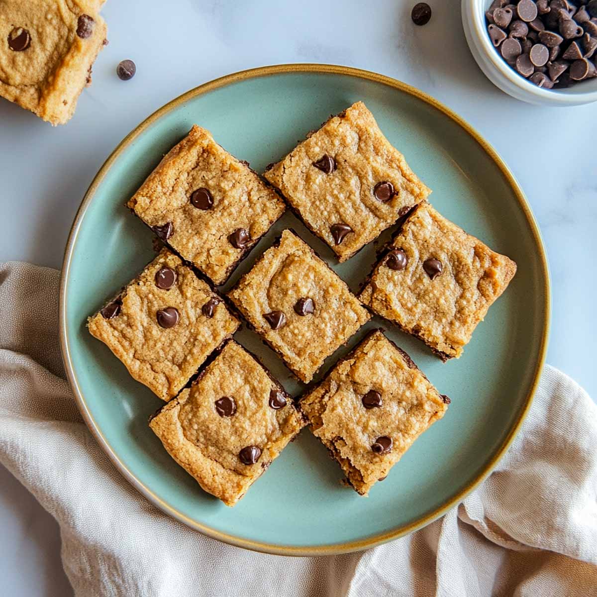 Golden sugar-free cookie bars with chocolate chips on sage green plate.