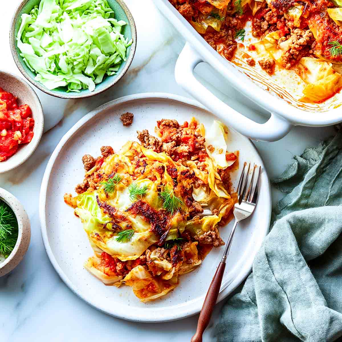 Turkey and cabbage casserole served on a plate with tomato sauce and caramelized edges.