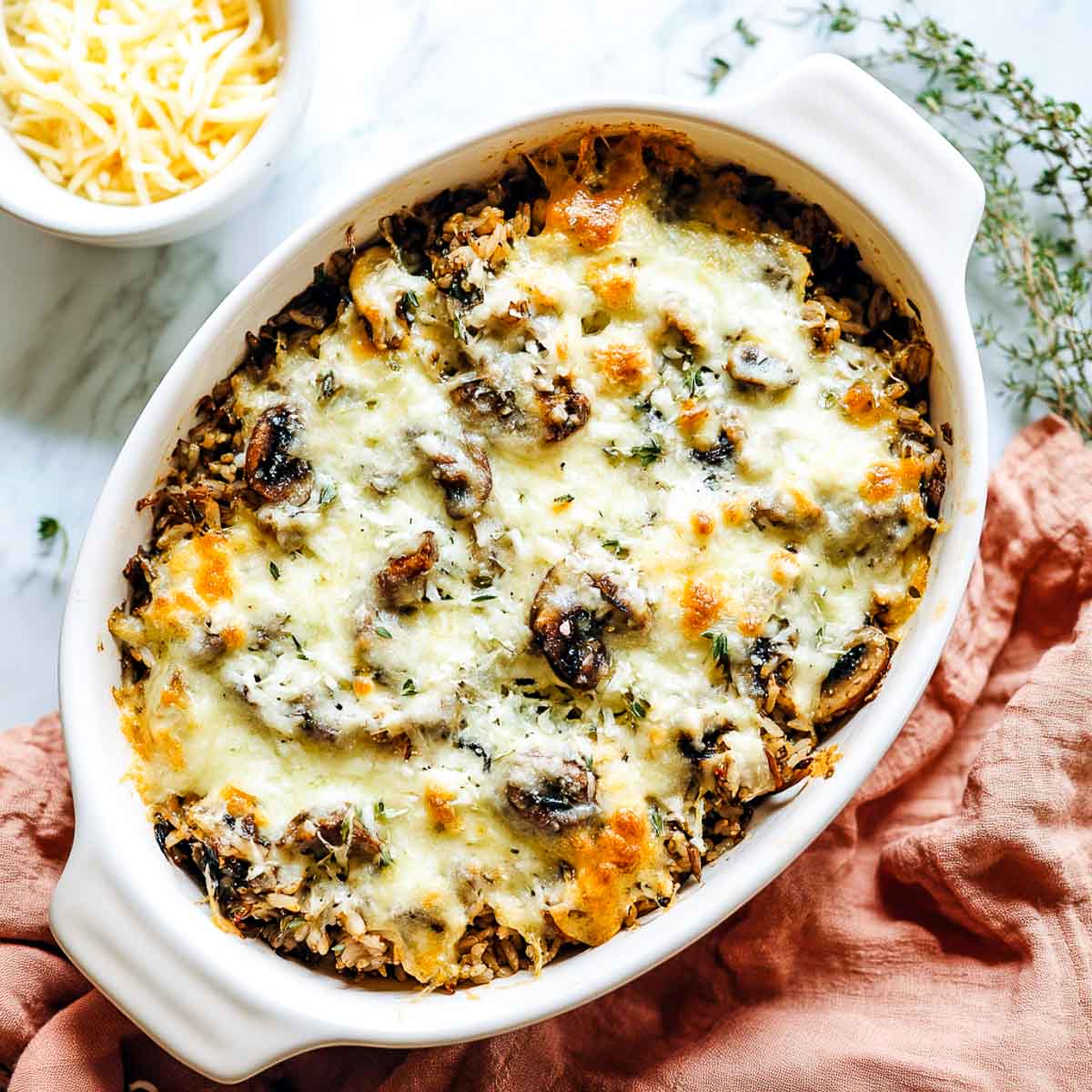 Baked wild rice and mushroom casserole with herbs in white ceramic dish.