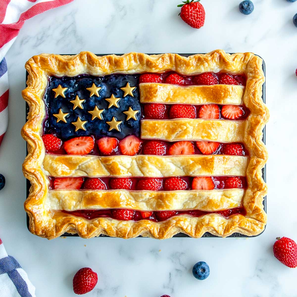 Rectangular berry flag pie decorated with blueberries, strawberries, and golden pastry stars.