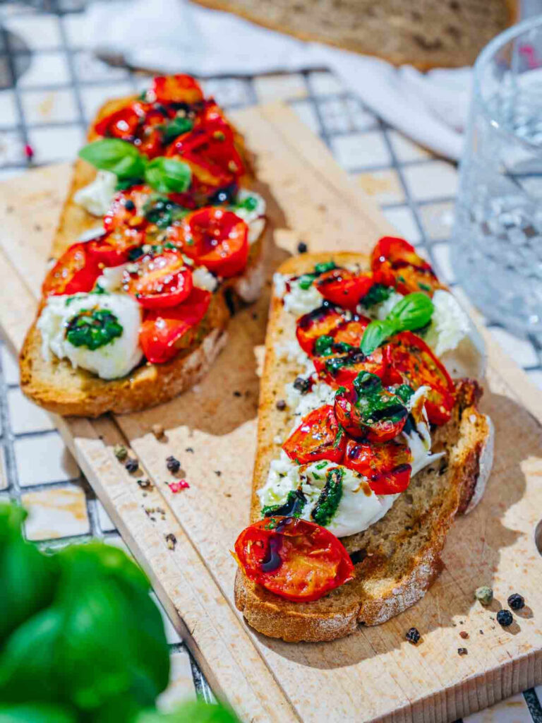 Two slices of bread topped with burrata and roasted tomatoes.