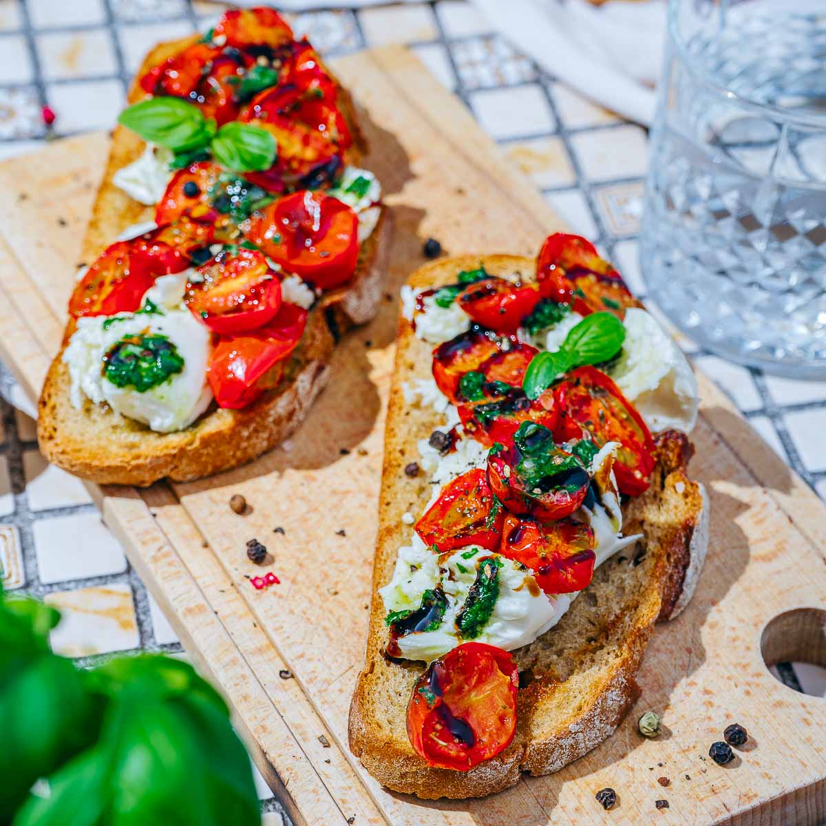 Burrata and roasted tomatoes toast on a wooden board.