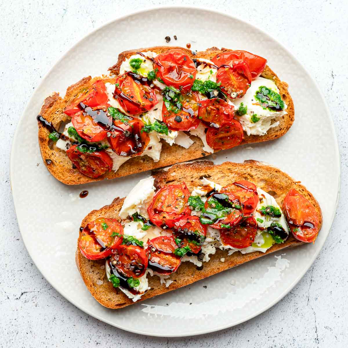 Assembled burrata toast on a white serving plate.