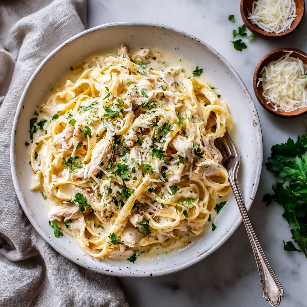 Creamy Crockpot Chicken Alfredo served in a wide bowl, topped with fresh parsley and shredded Parmesan.