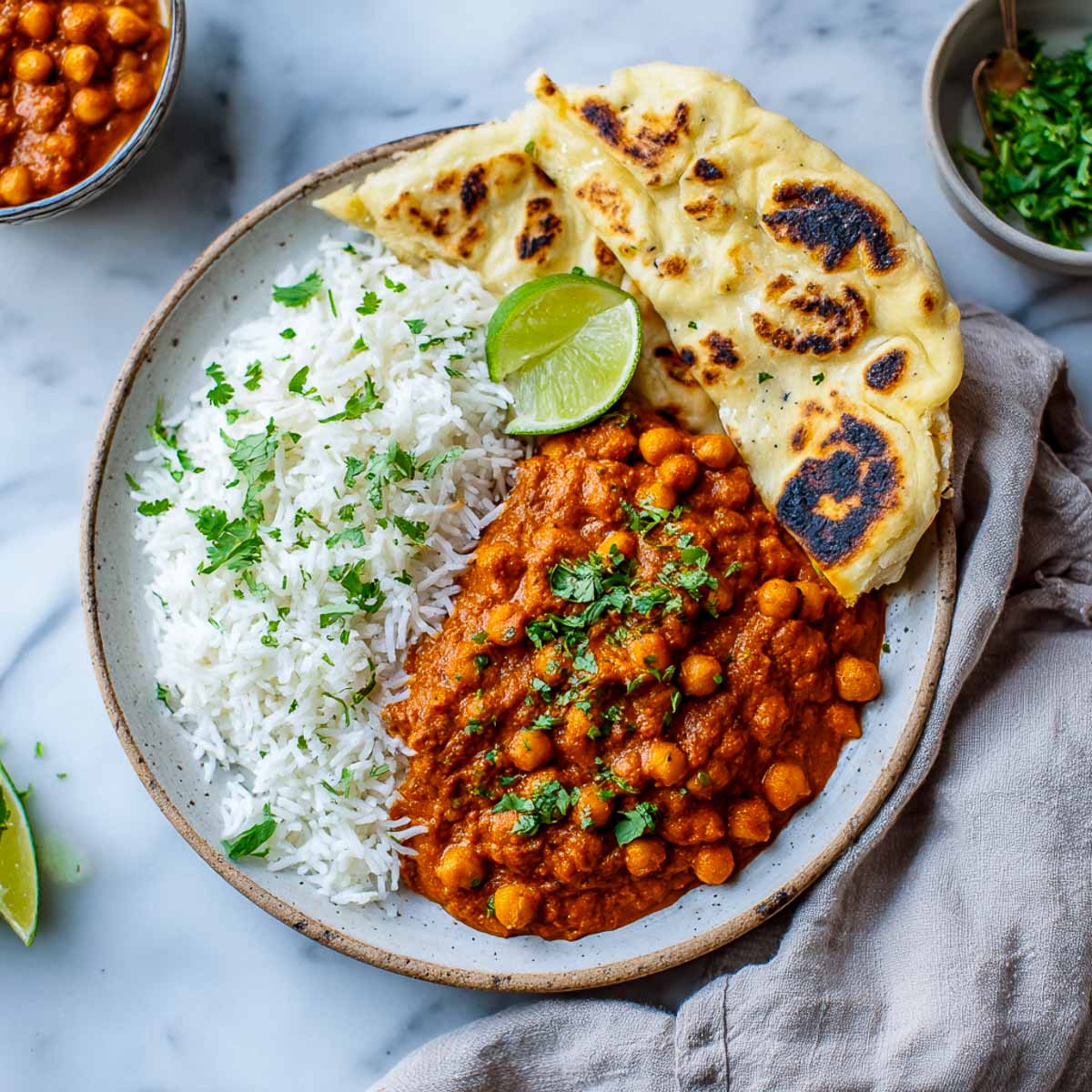 Chickpea tikka masala in a ceramic pate with naan and rice.