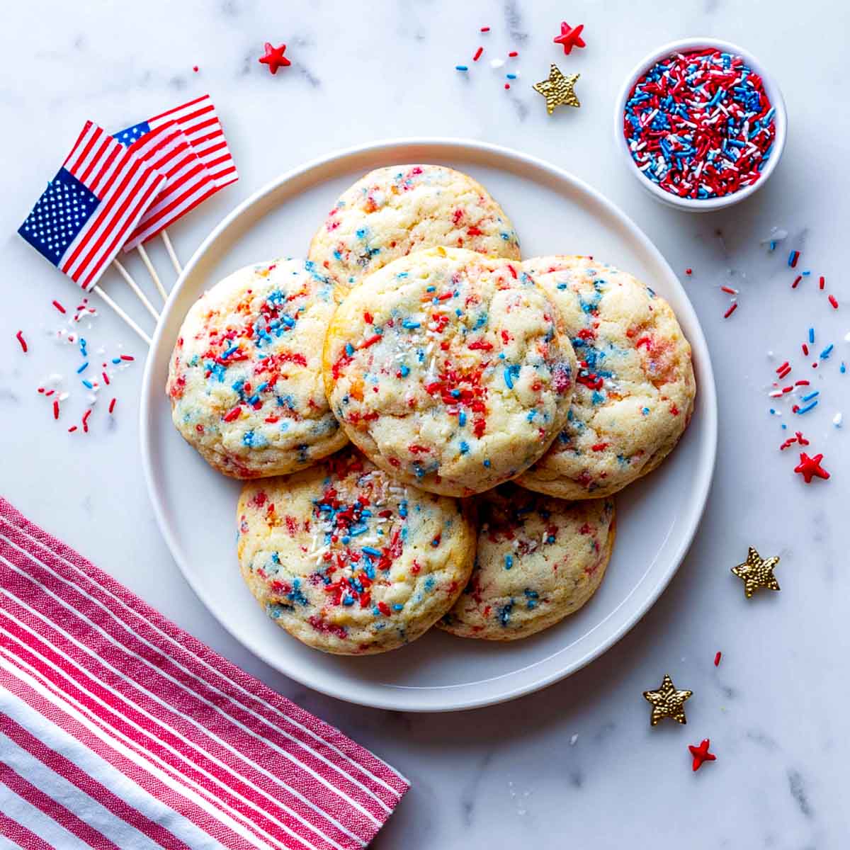 Top-down view of funfetti cookies with red, white, and blue sprinkles and patriotic props.