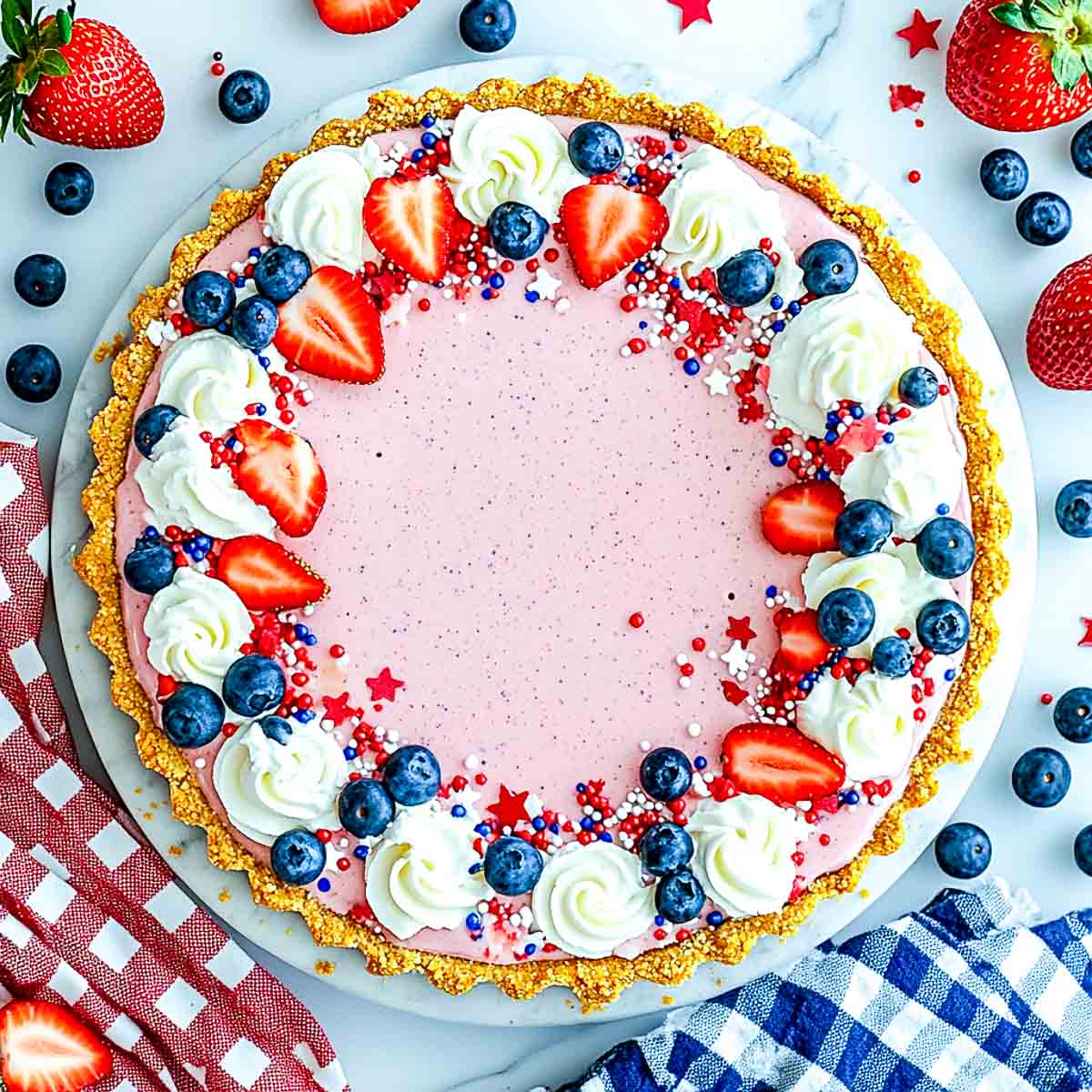 Top-down shot of no-bake 4th of July jello cream pie decorated with berries and sprinkles.