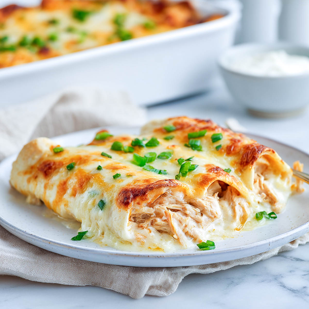Creamy chicken enchiladas topped with golden cheese and green onions.