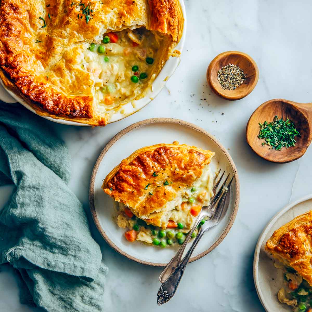 Chicken pot pie slice on plate with golden crust and creamy filling.