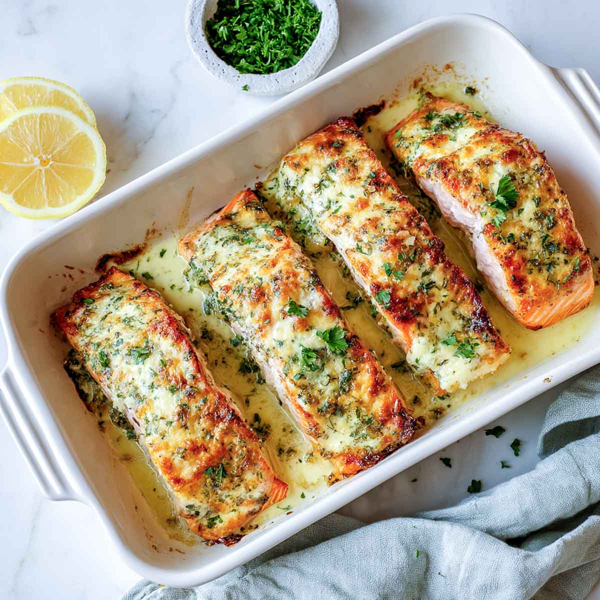 Baked salmon fillets topped with golden creamy herb cheese sauce.