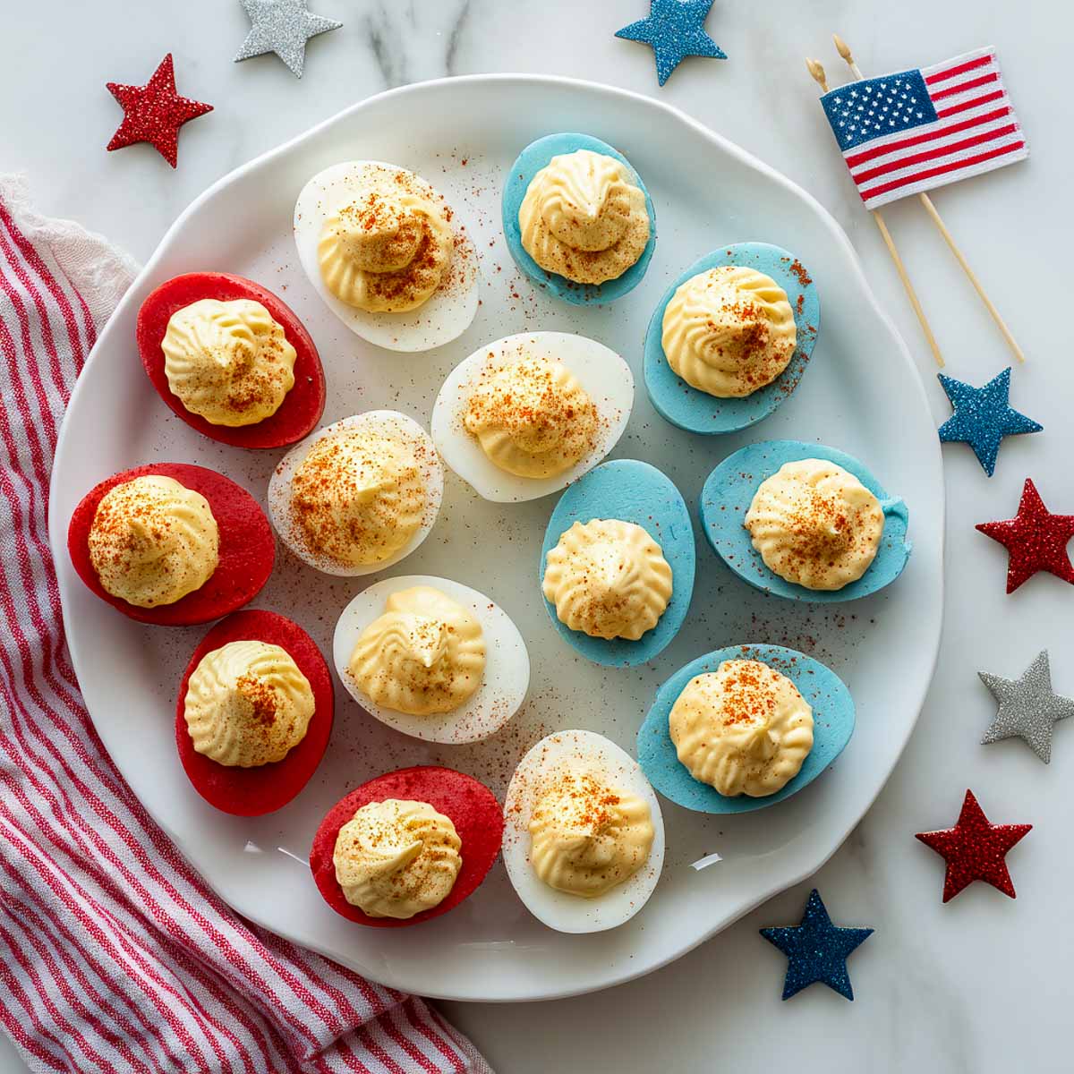 Deviled eggs with red, white, and blue dyed whites, topped with pale yellow filling and paprika.