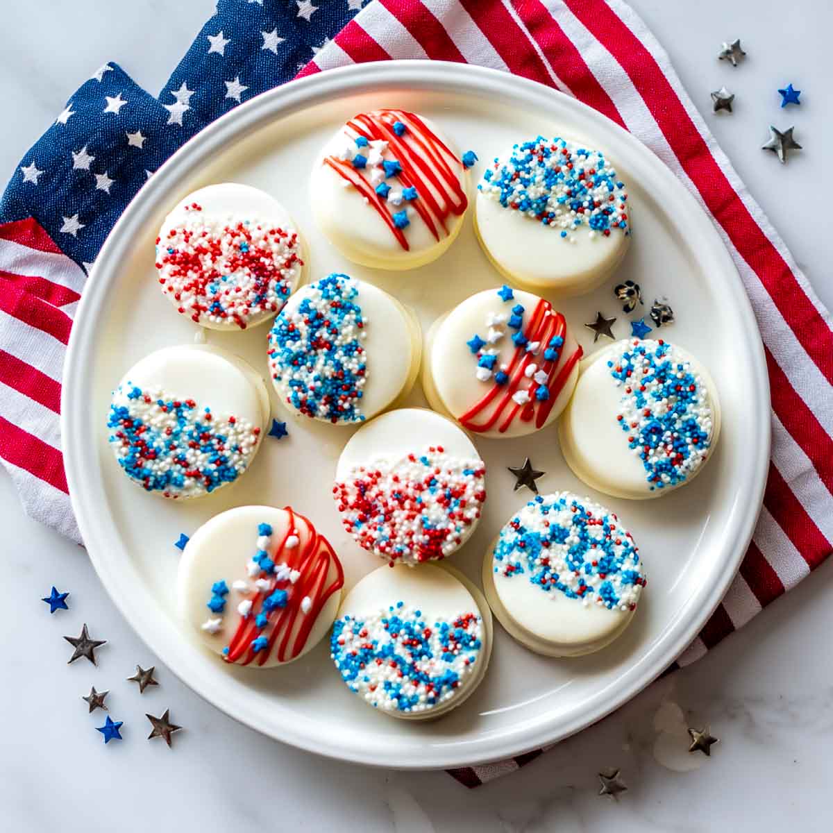 Top-down view of white chocolate-dipped Oreos with red, white, and blue sprinkles.