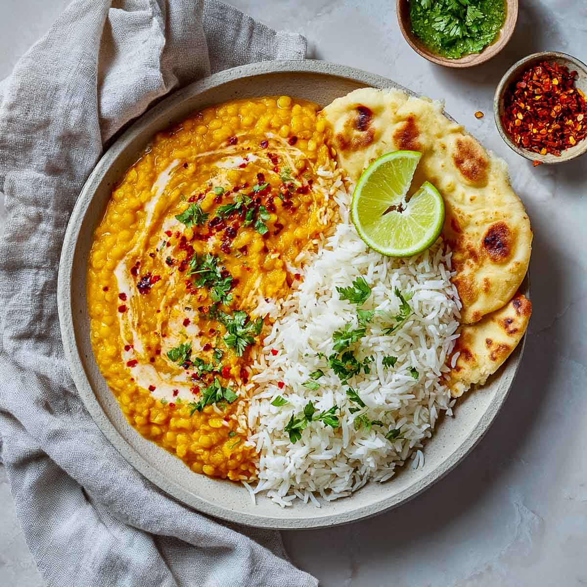 Plate of red lentil dahl and rice with naan and green chutney.
