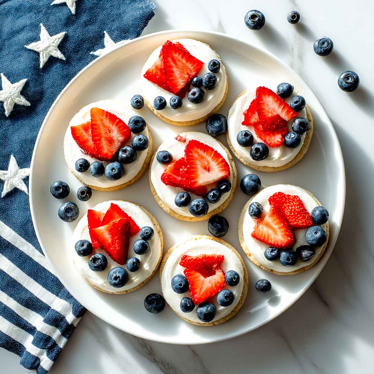Top-down view of mini fruit pizzas topped with strawberries and blueberries.