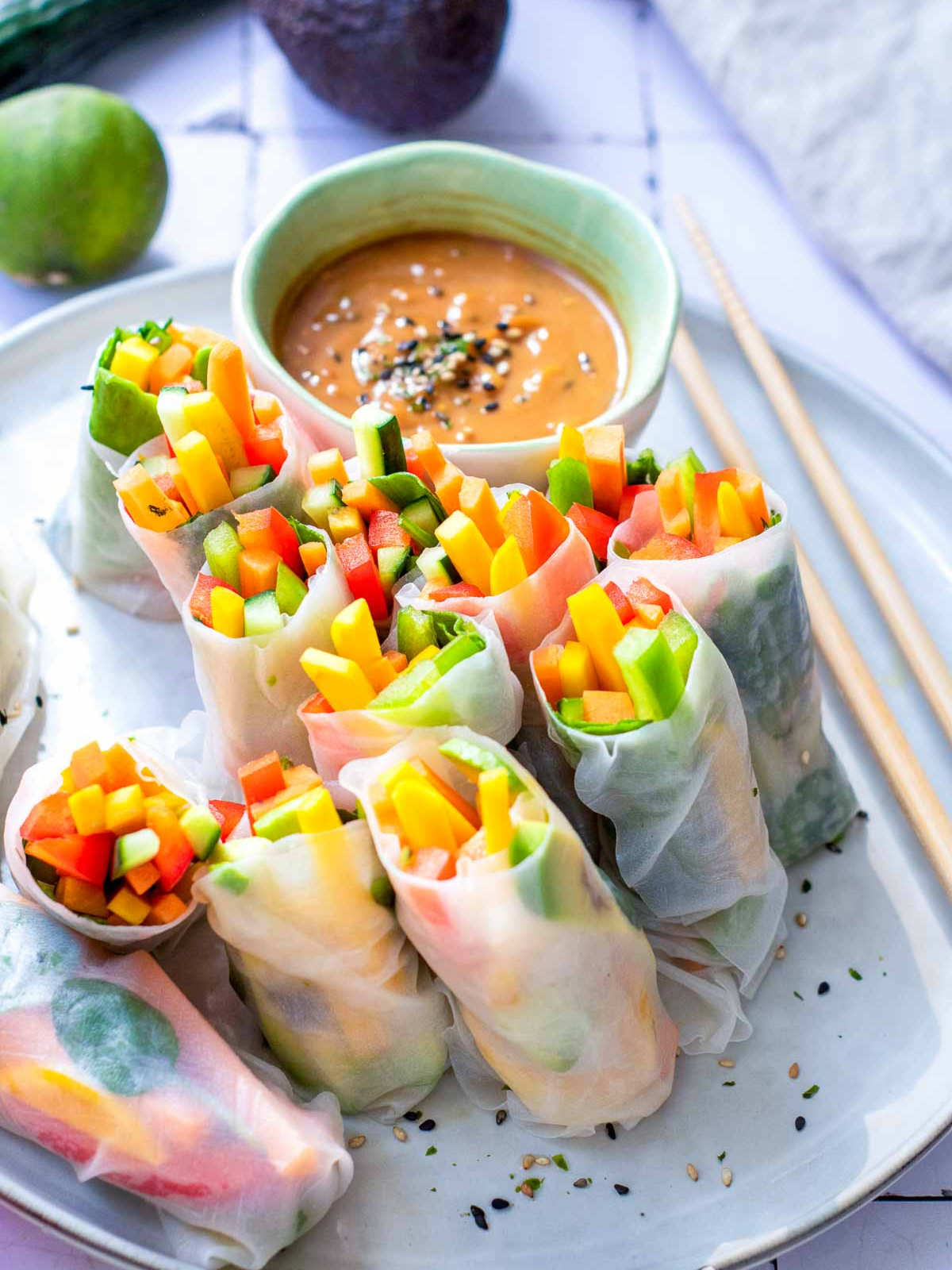 Rice paper rolls on a white plate served with sauce.