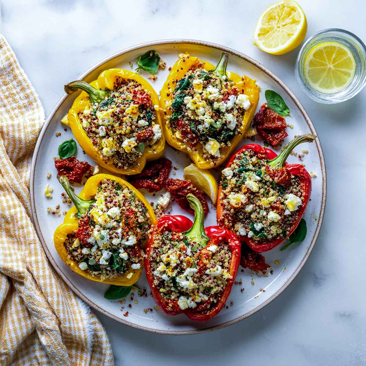 Stuffed bell peppers with quinoa, spinach, and feta on white plate.