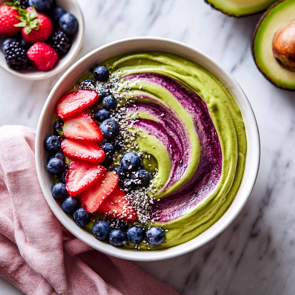 Avocado berry smoothie bowl with fruit toppings and a purple swirl on top.