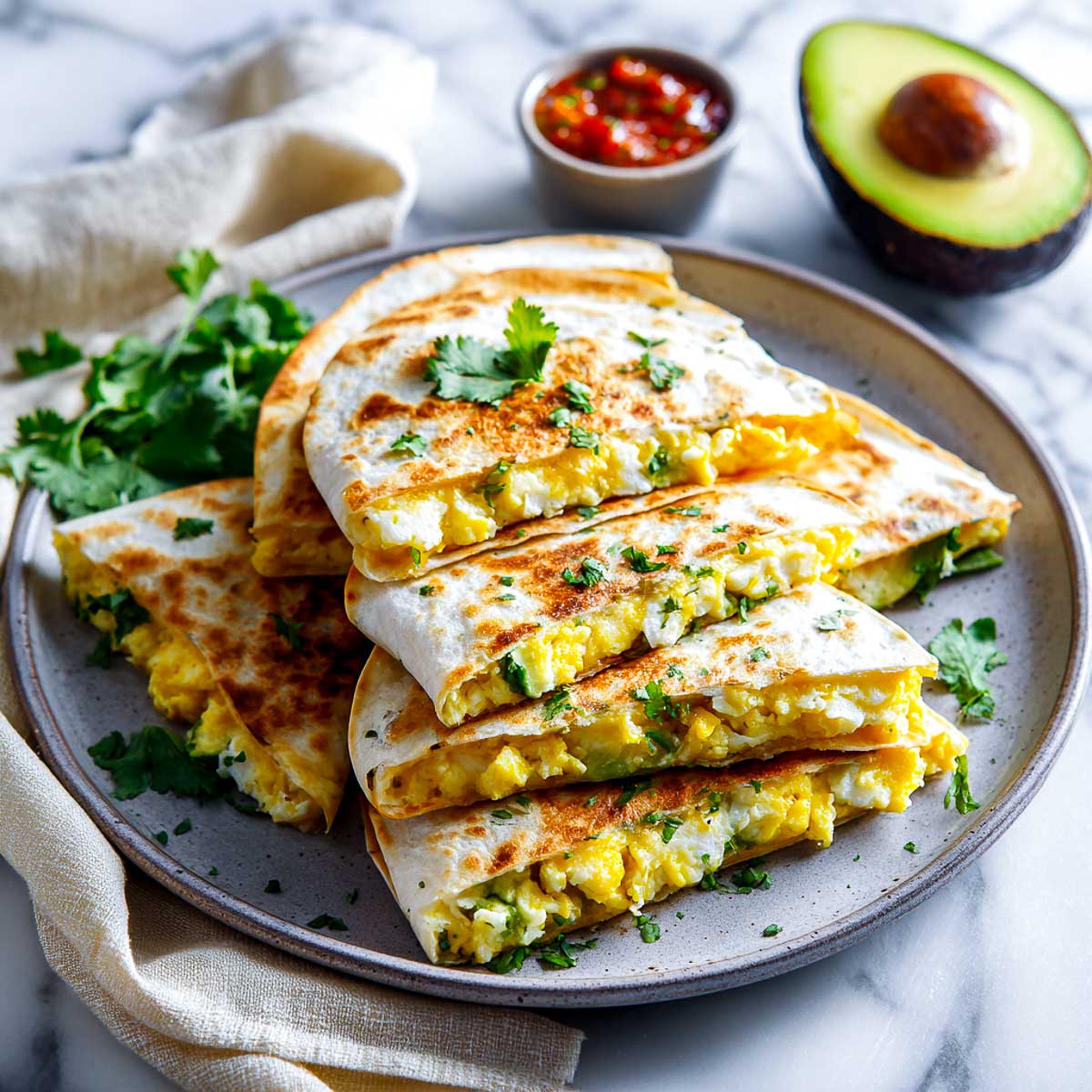 Crispy breakfast quesadillas filled with avocado, eggs, and cheese on plate.