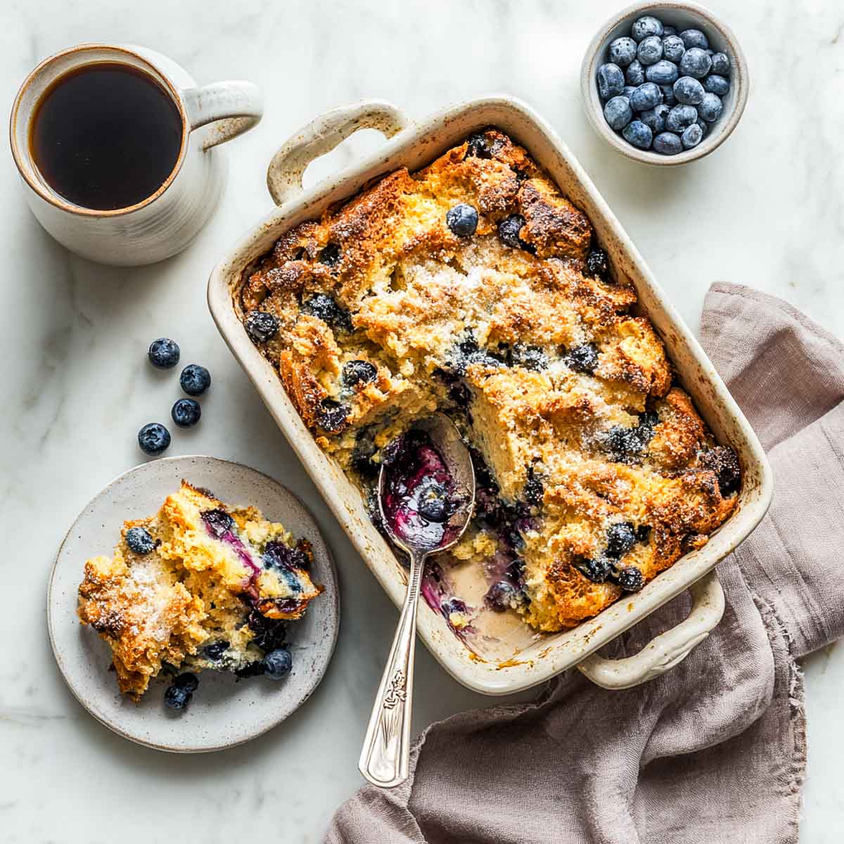 Top-down view of blueberry French toast casserole with one portion served on a side plate.