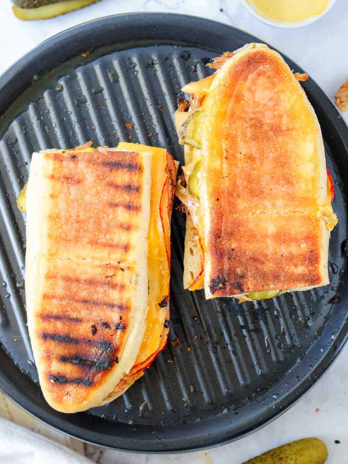 Fully grilled Cuban sandwiches on the press with golden brown crust.
