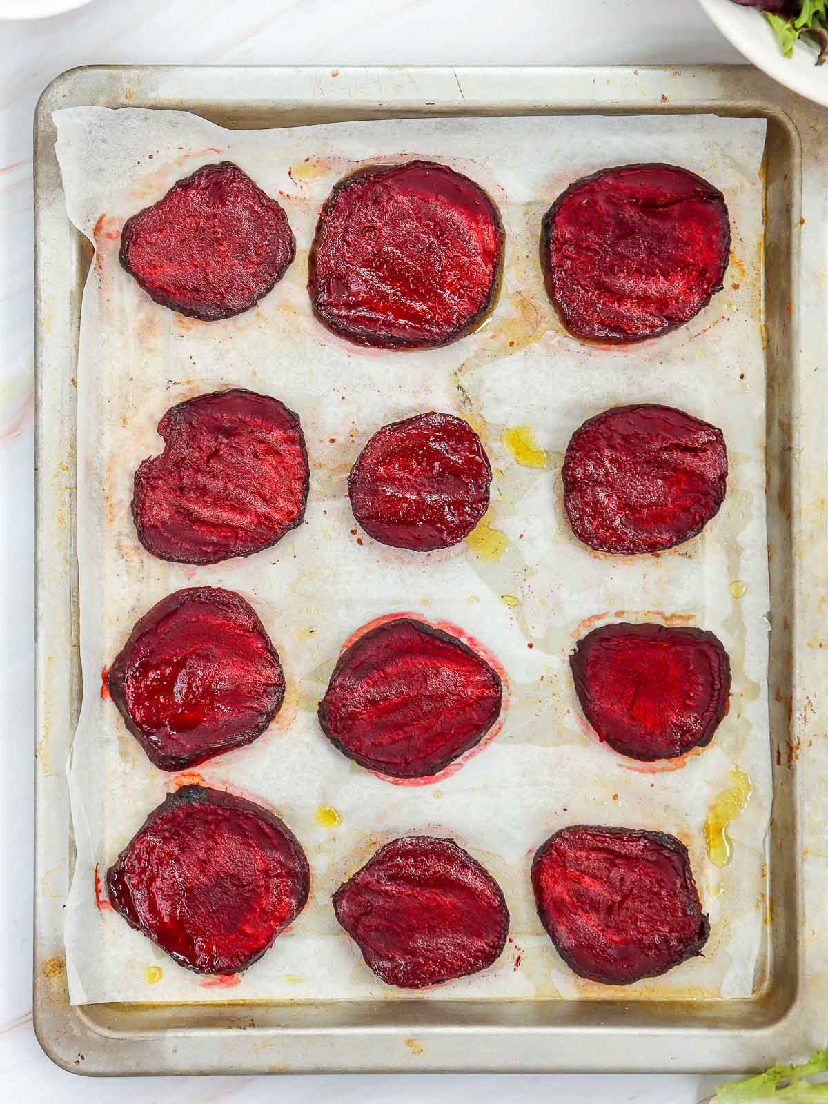 Beetroot slices arranged on a parchment-lined baking sheet after cooking.