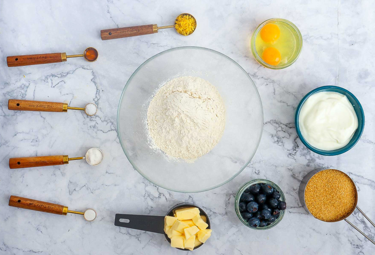 Flat lay of lemon blueberry bundt cake ingredients arranged on a marble surface.