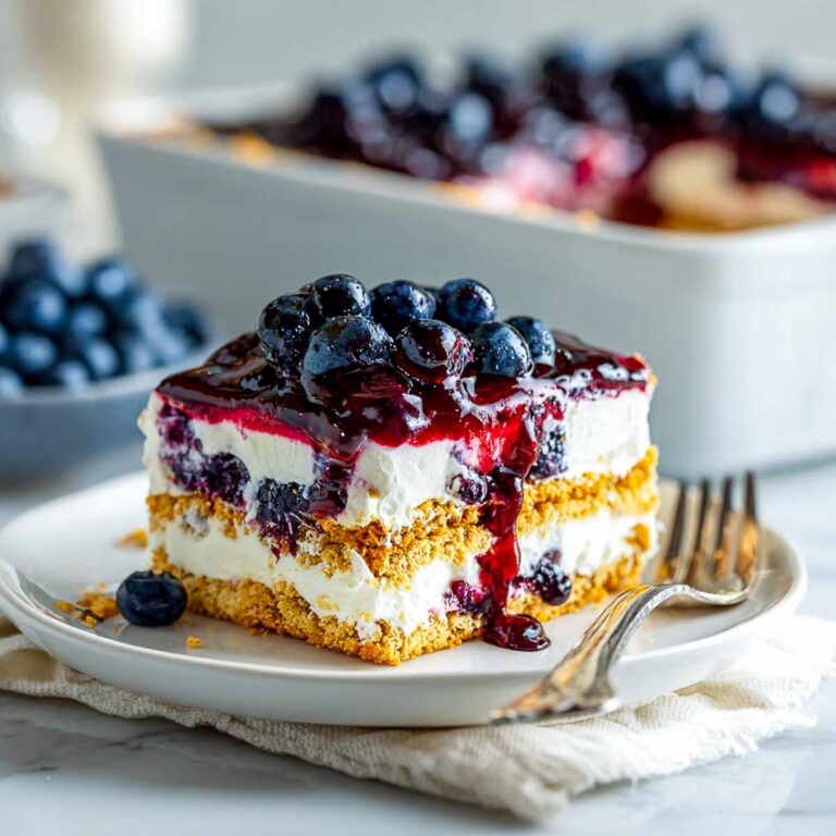 Slightly angled view of blueberry icebox cake slice with whipped topping and graham layers.
