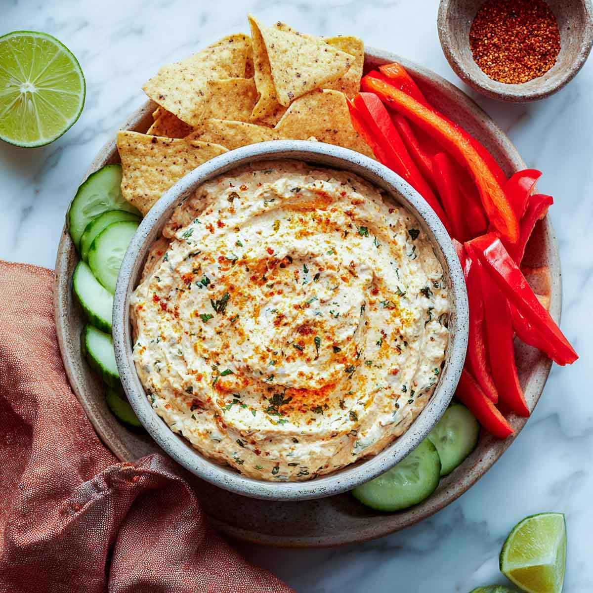 Creamy ranch dip with herbs and spices served with peppers, chips, and cucumbers.