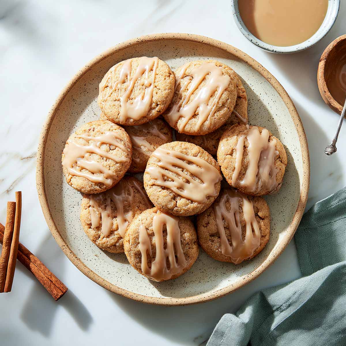 Top-down view of glazed apple cider cookies arranged on a speckled plate.