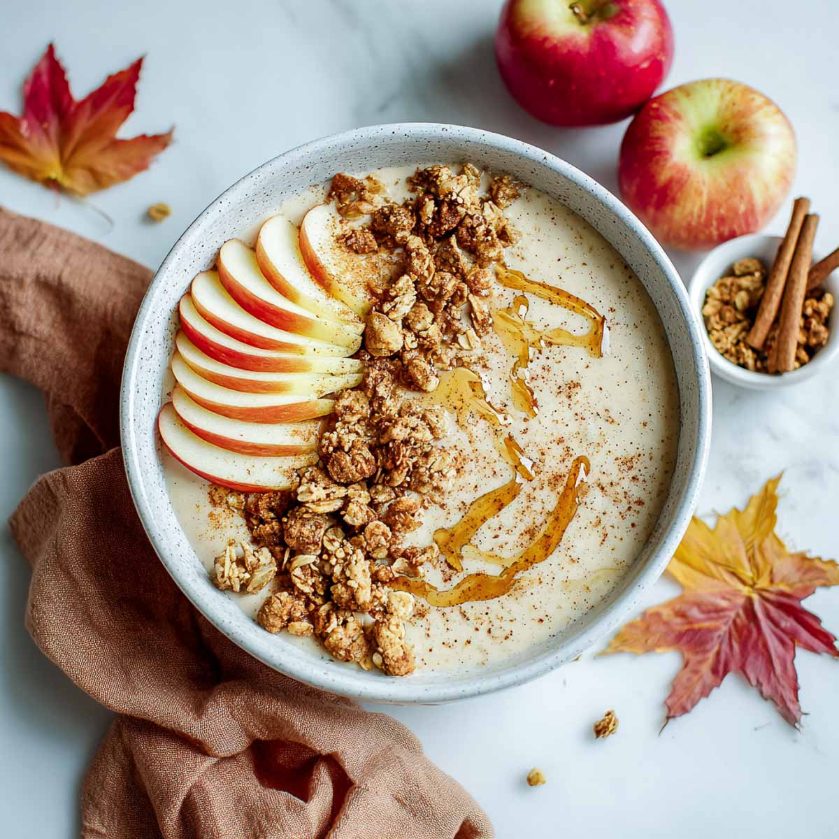 Apple pie smoothie bowl topped with sliced apples and granola.