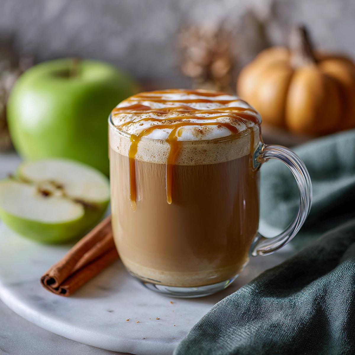Caramel apple latte with foam, caramel drizzle in a glass mug.