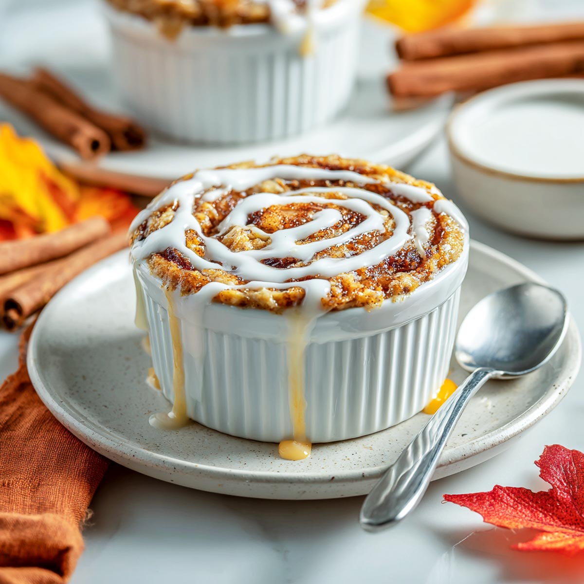 Single-serving cinnamon roll baked oats in white ramekin with icing swirl.