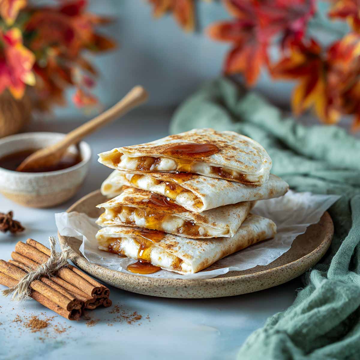 Stacked maple cinnamon quesadillas drizzled with syrup on stoneware plate.