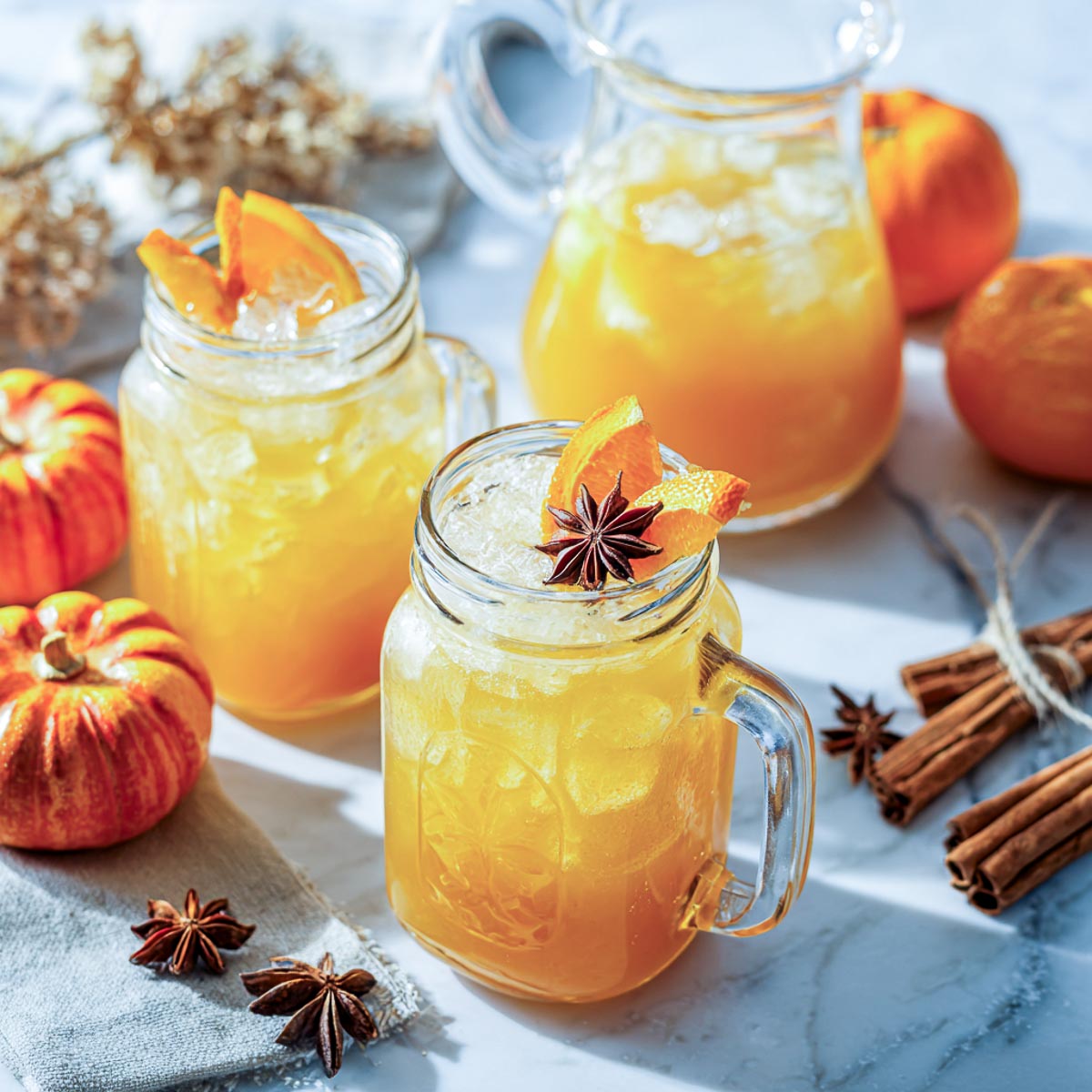 Pumpkin cider rum punch in mason jars with orange slices and star anise.