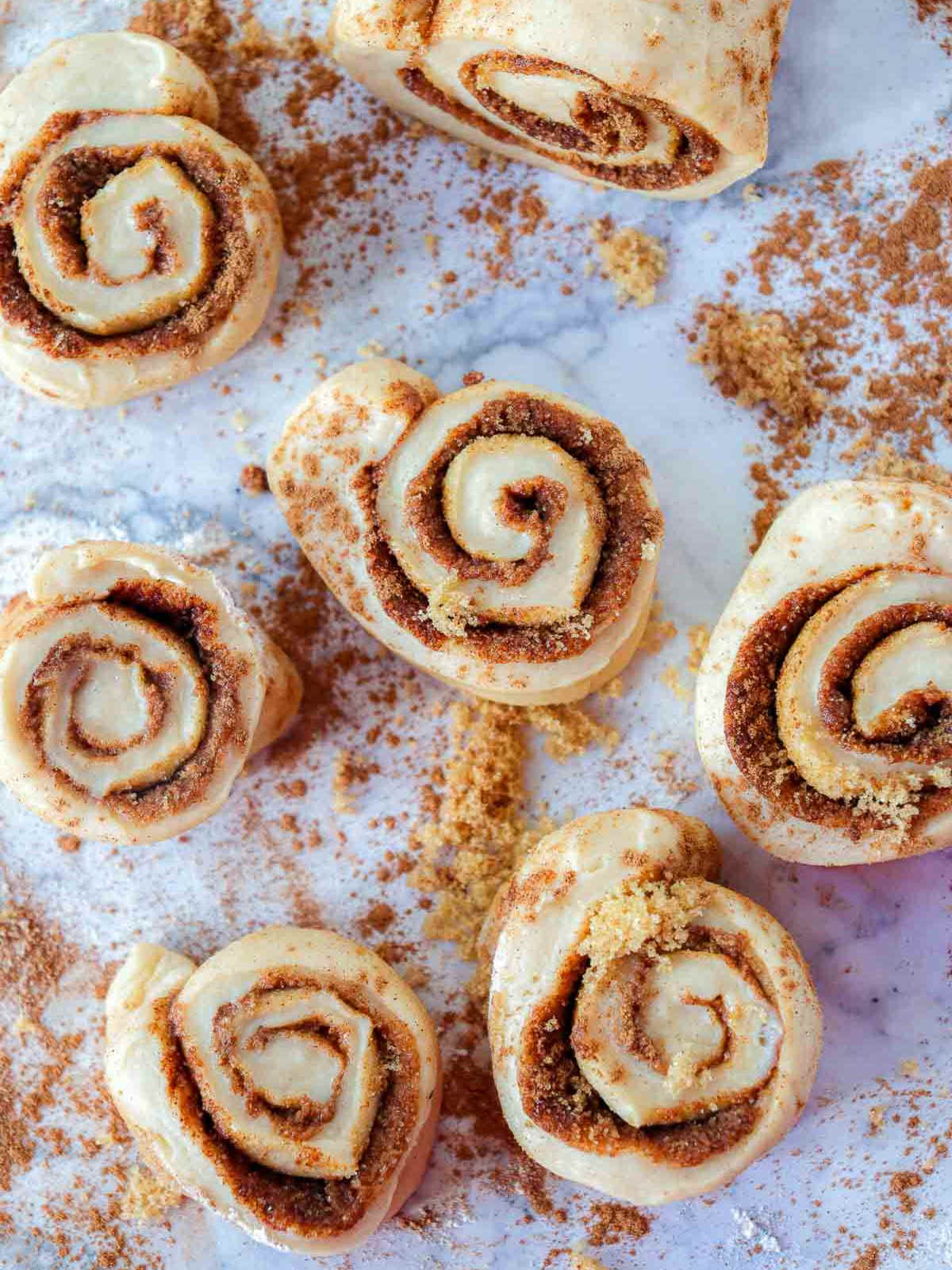 Close-up of cut pumpkin cinnamon roll slices on a floured surface, showing rich cinnamon sugar filling.