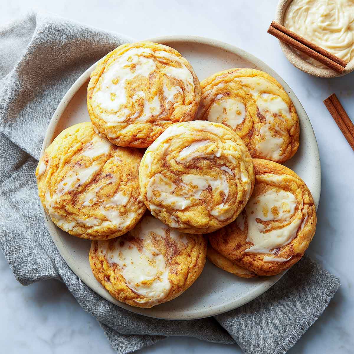 Pumpkin cookies with baked-in cream cheese swirls and golden edges.