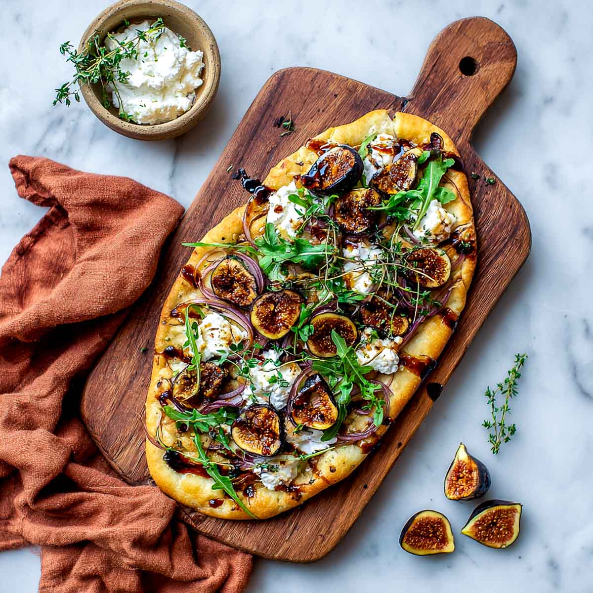 Top-down view of roasted fig flatbread with red onions and fresh thyme.