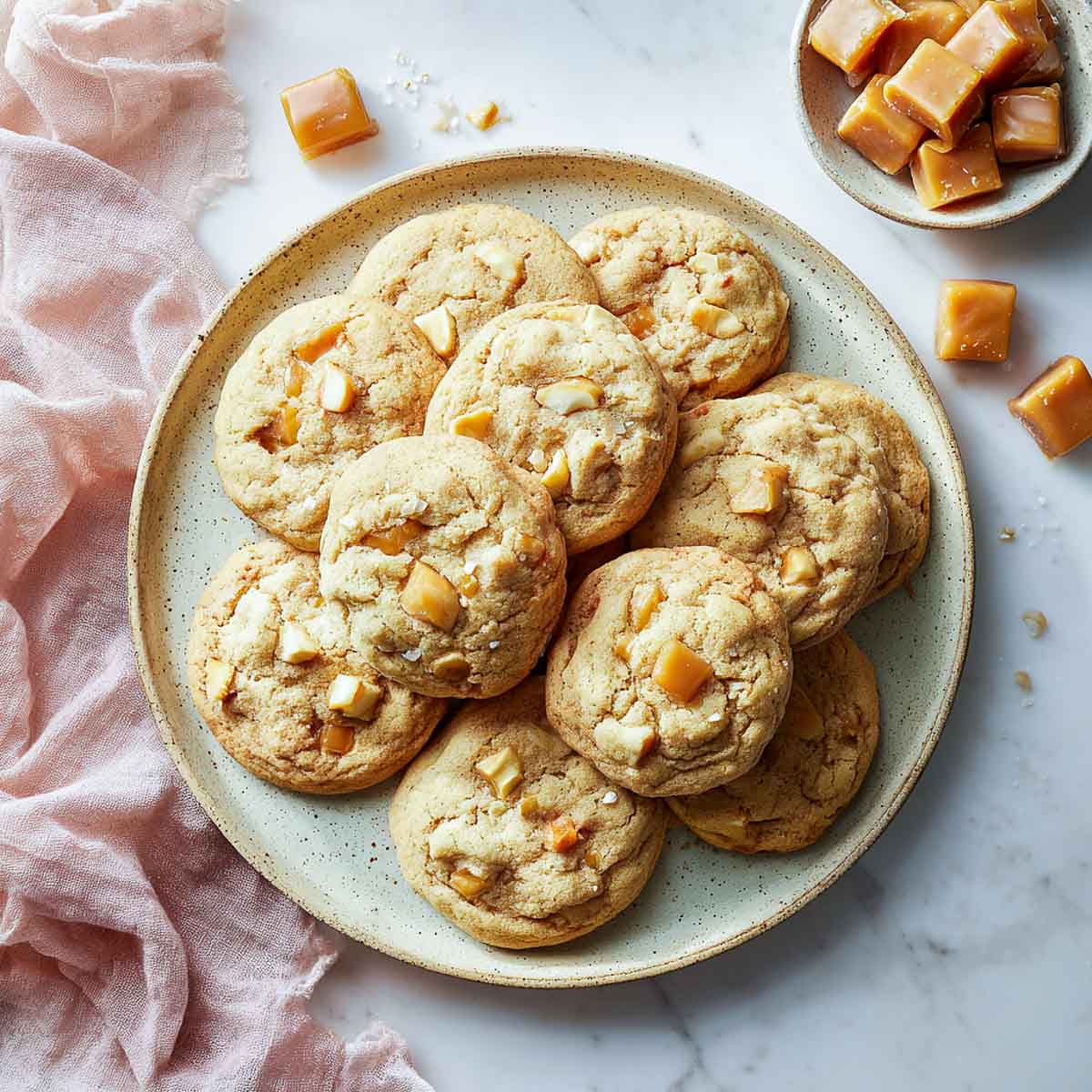 Soft-baked vegan cookies with caramel chunks and apple pieces on a plate.