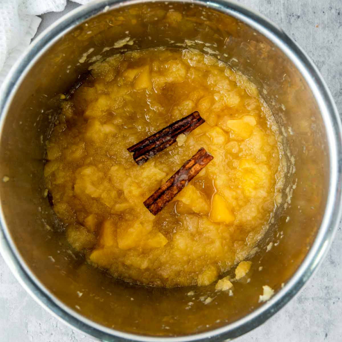 Cooked apples with cinnamon sticks inside the Instant Pot, ready to mash for applesauce.