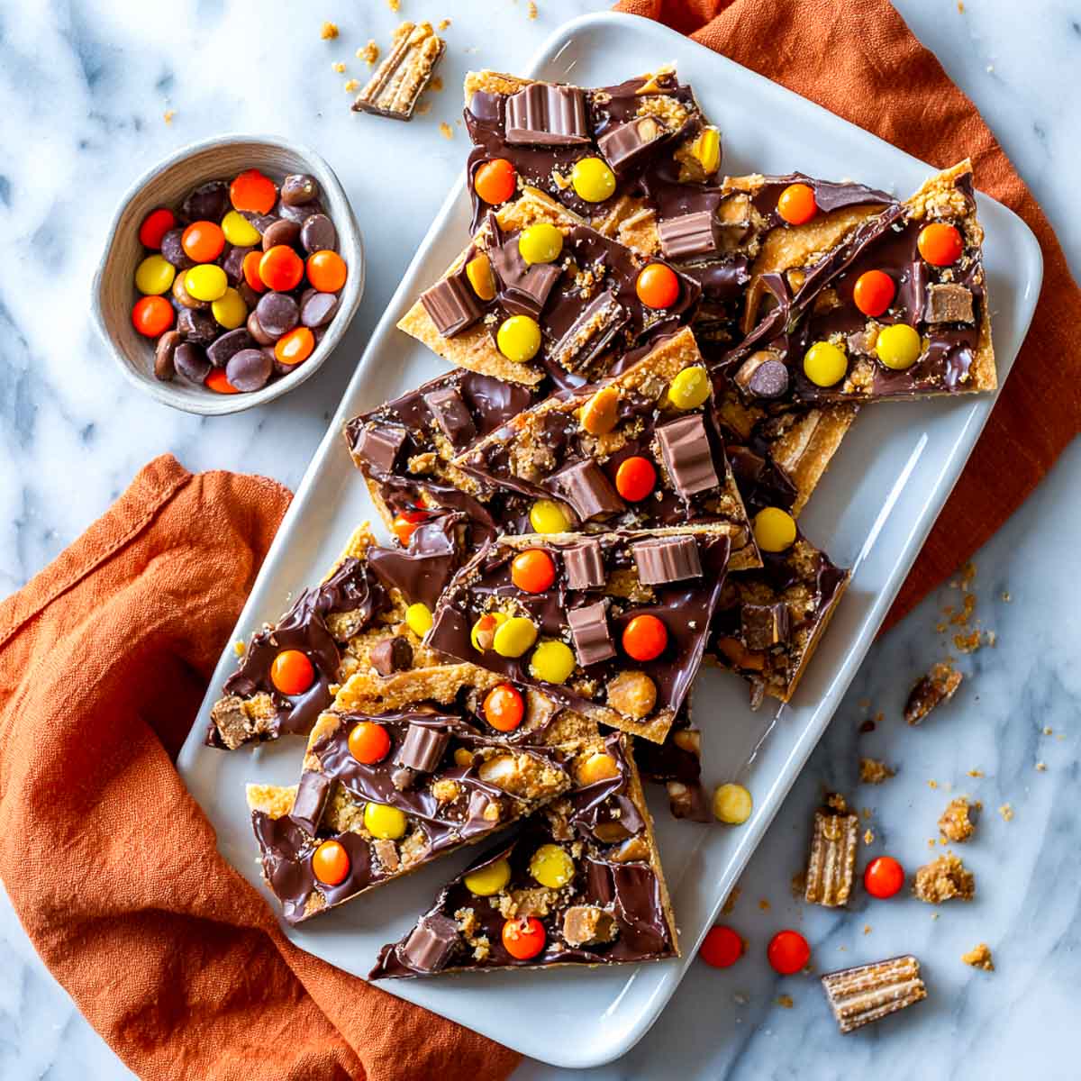 Candy cracker toffee shards topped with Halloween candy on a plate.