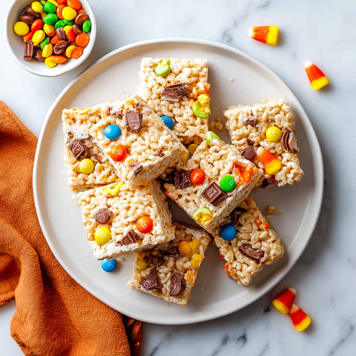 Rice Krispies treats with colorful Halloween candies on a plate.