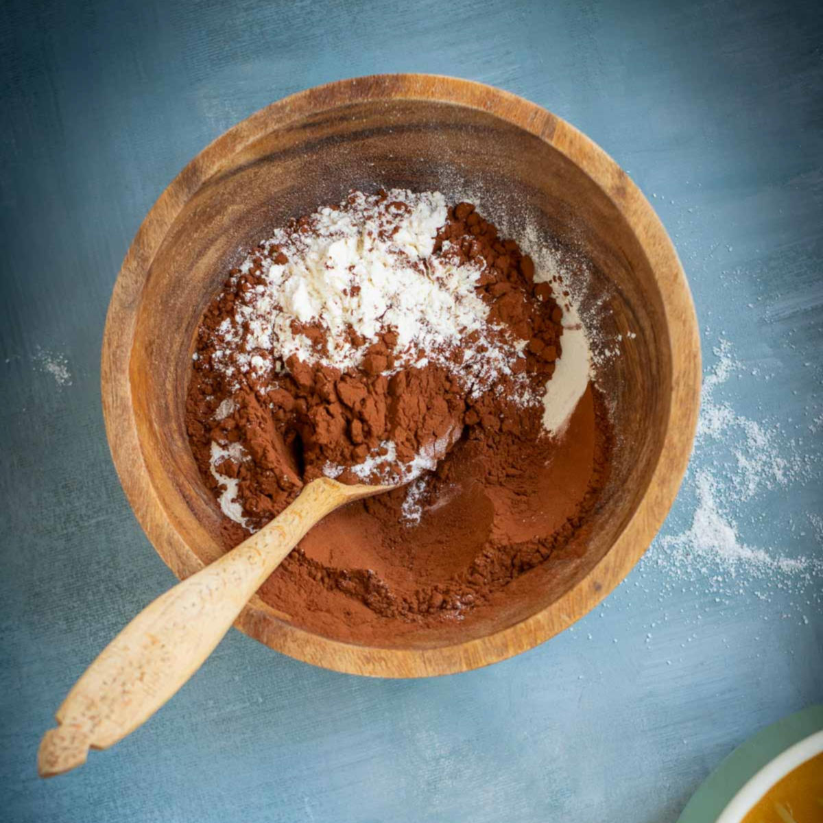 Wooden bowl with cocoa powder and flour mixture ready to be combined for brownie batter.