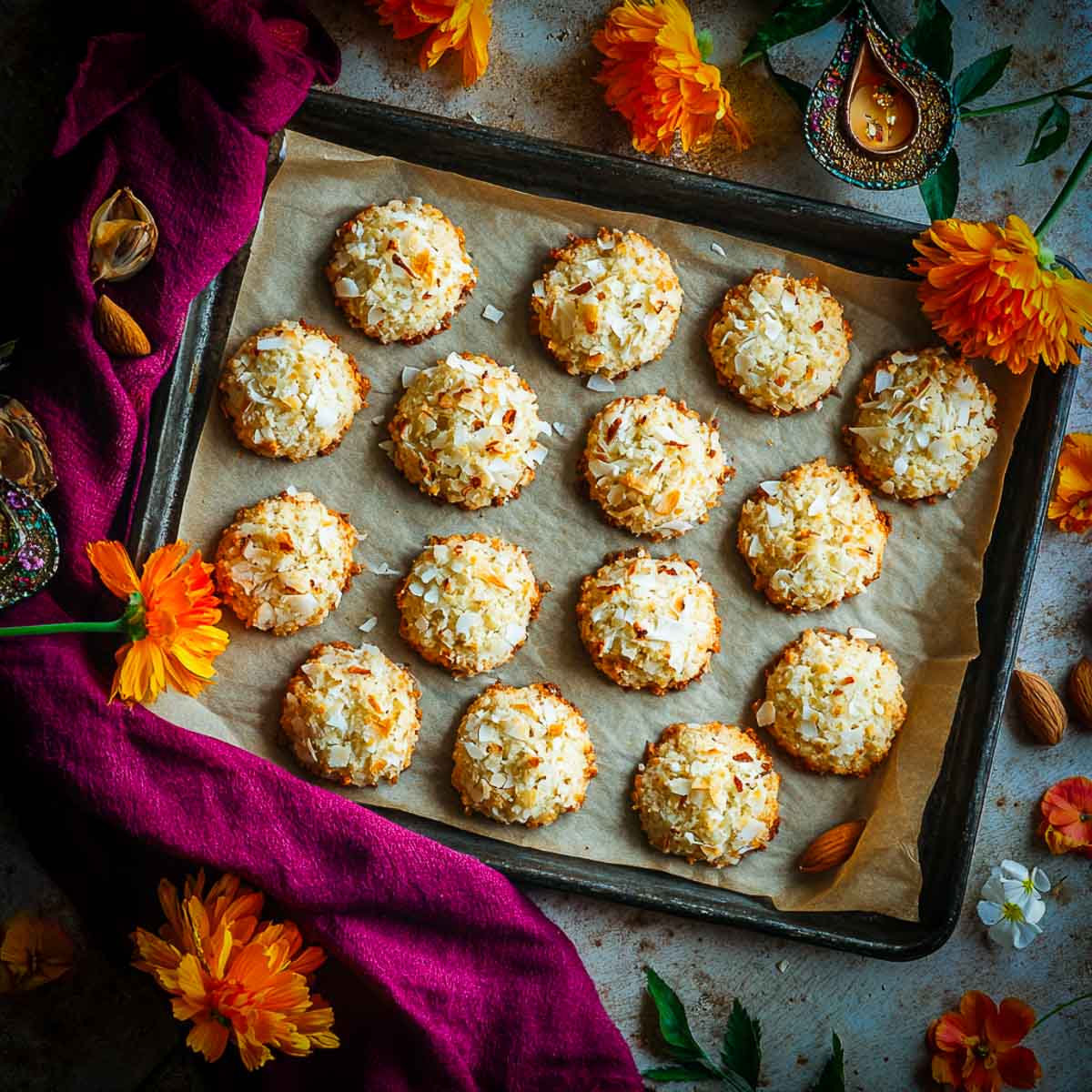 Tray of freshly baked coconut cardamom cookies topped with shredded coconut.