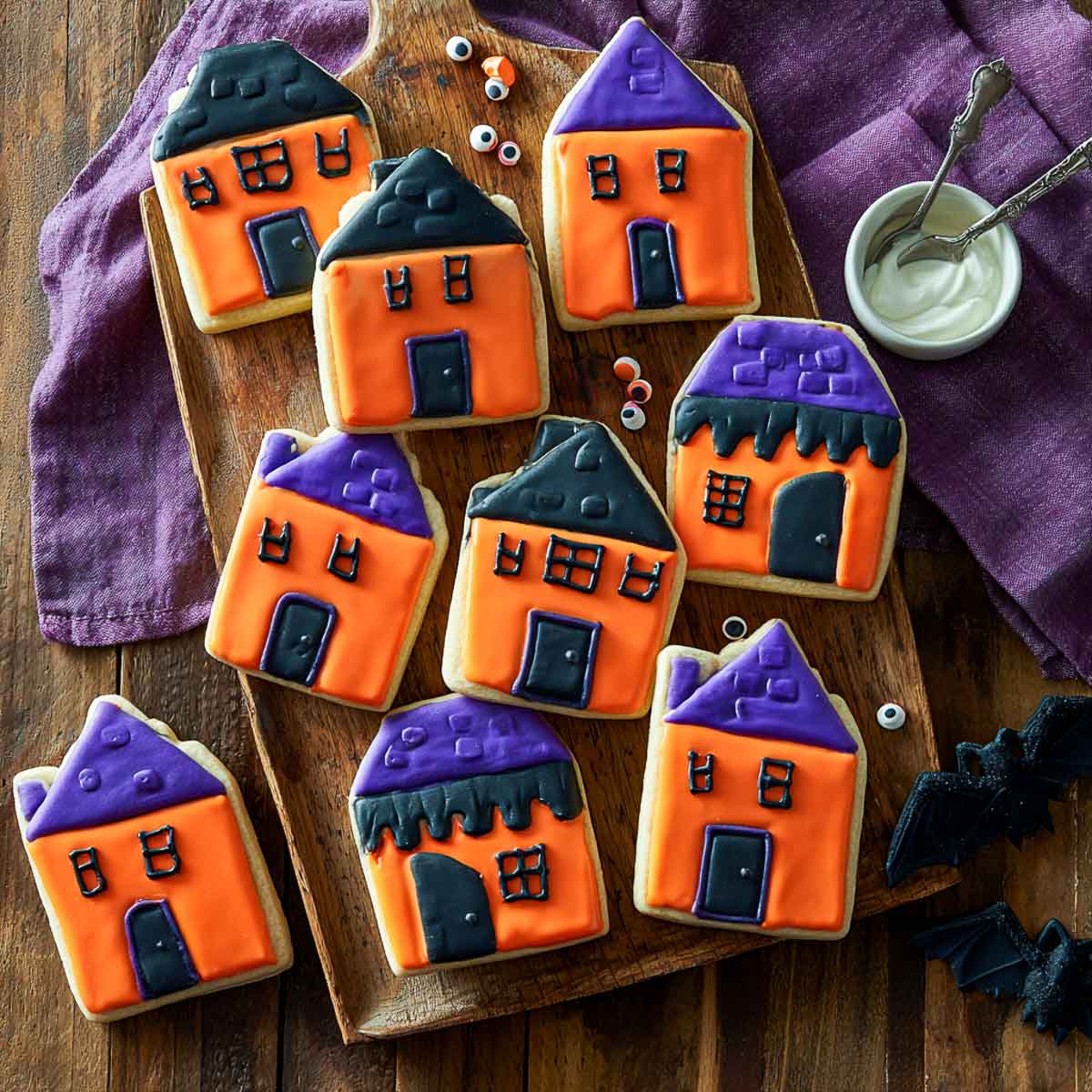 Top-down view of haunted house sugar cookies decorated with orange, purple, and black icing.