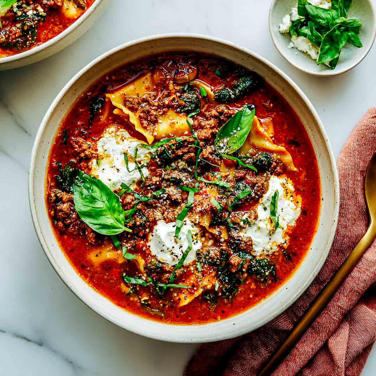 Bowl of vegan lasagna soup with noodles, vegan ricotta, basil, and tomato broth.